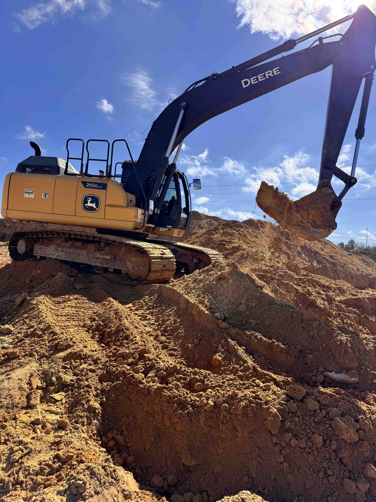 Our excavator digging into a pile of sand on a job site